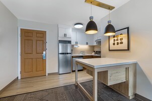 Una cocina moderna con armarios blancos, electrodomésticos de acero inoxidable e iluminación colgante.