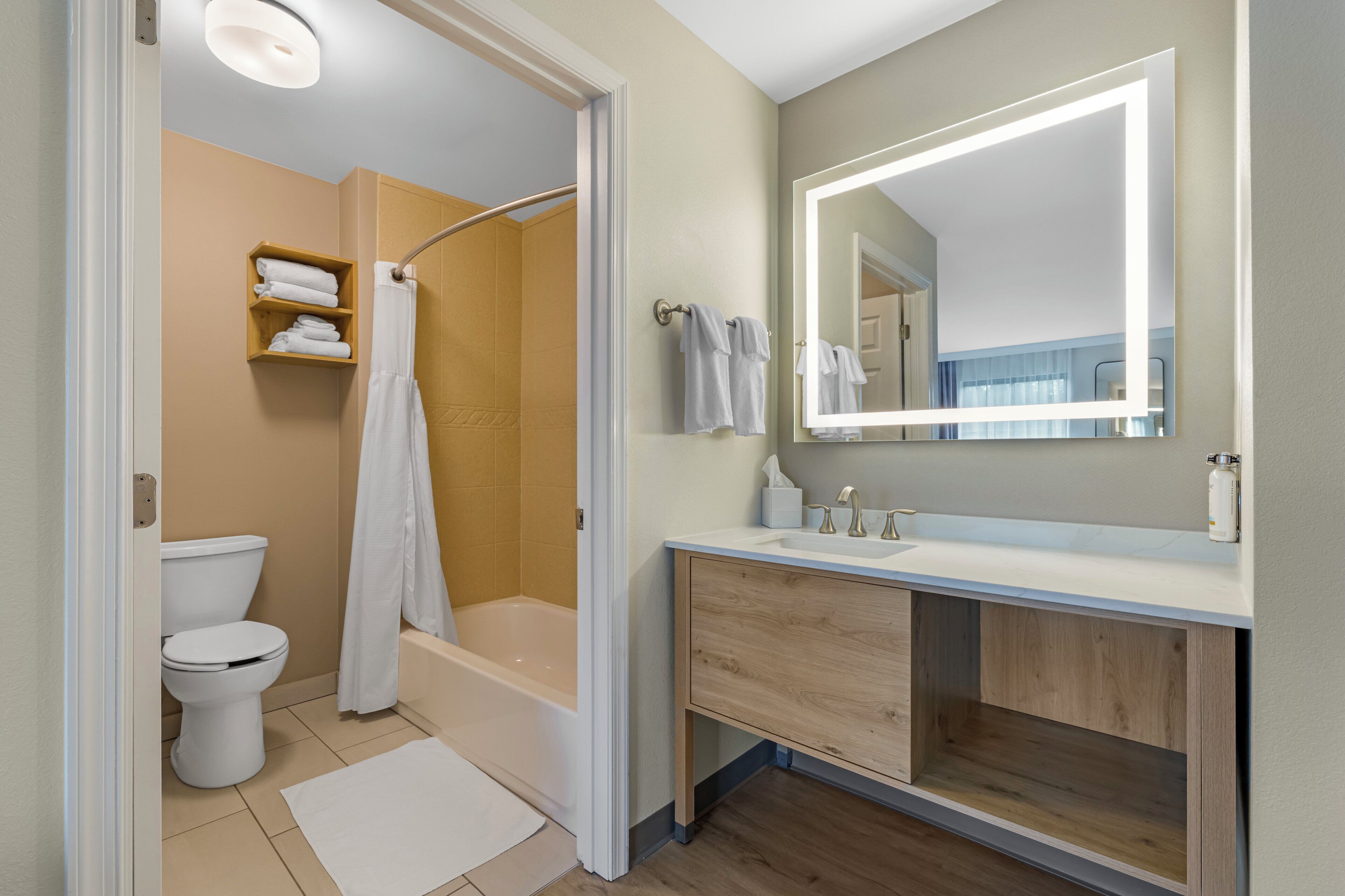 Ein Badezimmer mit Dusche, Toilette und Waschtisch mit Spiegel.