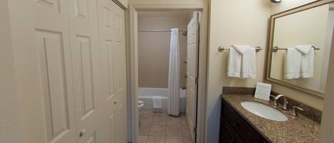 A hotel bathroom with a shower, toilet, sink, and towel rack.