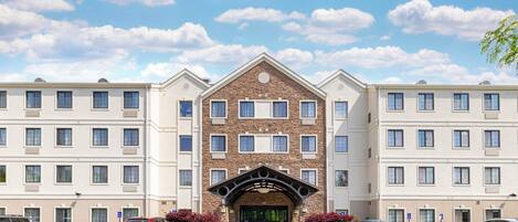 A multi-story hotel with a central entrance featuring a stone facade and a modern archway.