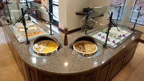 A buffet area with multiple food stations, including a section with tortillas and another with scrambled eggs.