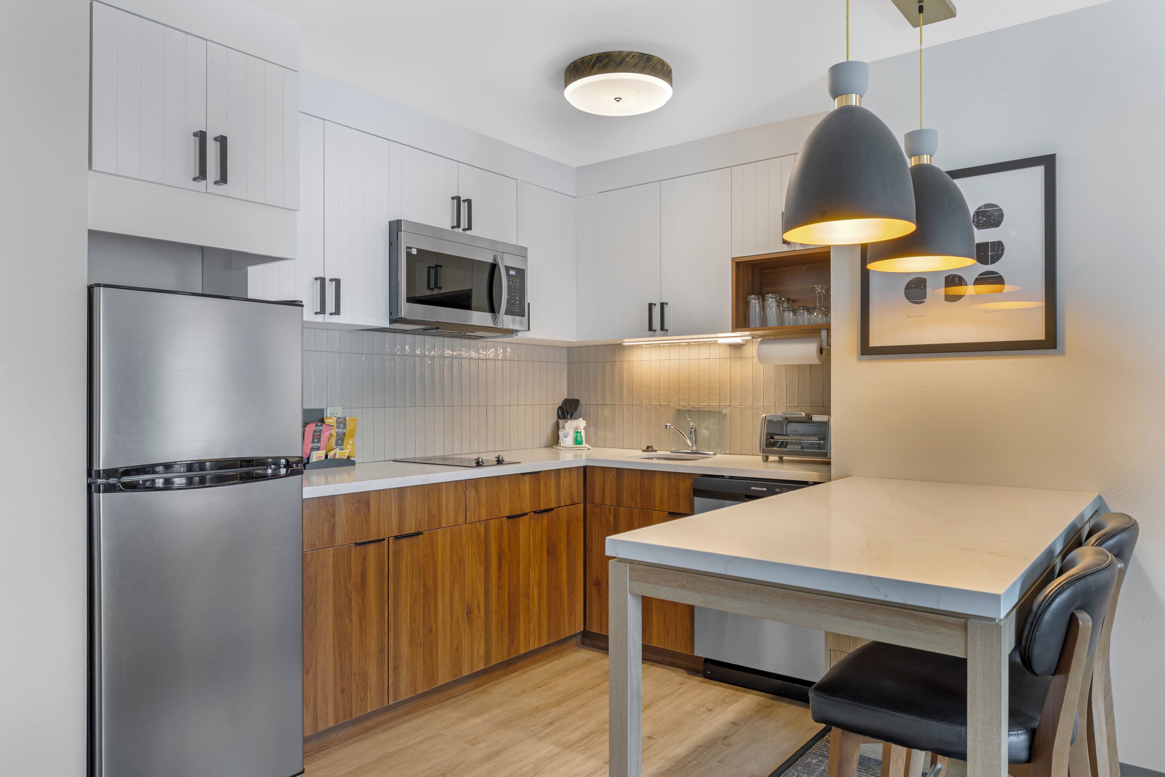 Una cocina moderna con electrodomésticos de acero inoxidable, armarios de madera e iluminación colgante.