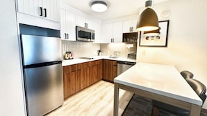 A modern kitchen with white cabinets, stainless steel appliances, and a wooden countertop.