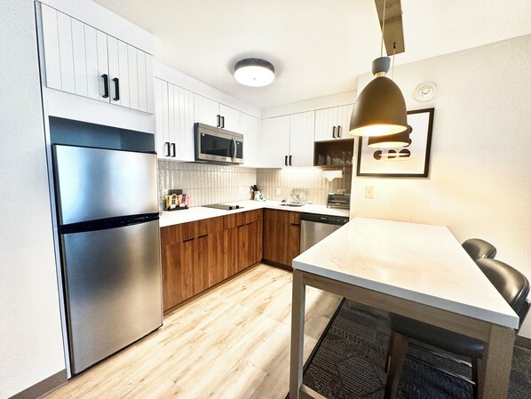 Une cuisine moderne avec des armoires blanches, des appareils en acier inoxydable et un plan de travail en bois.