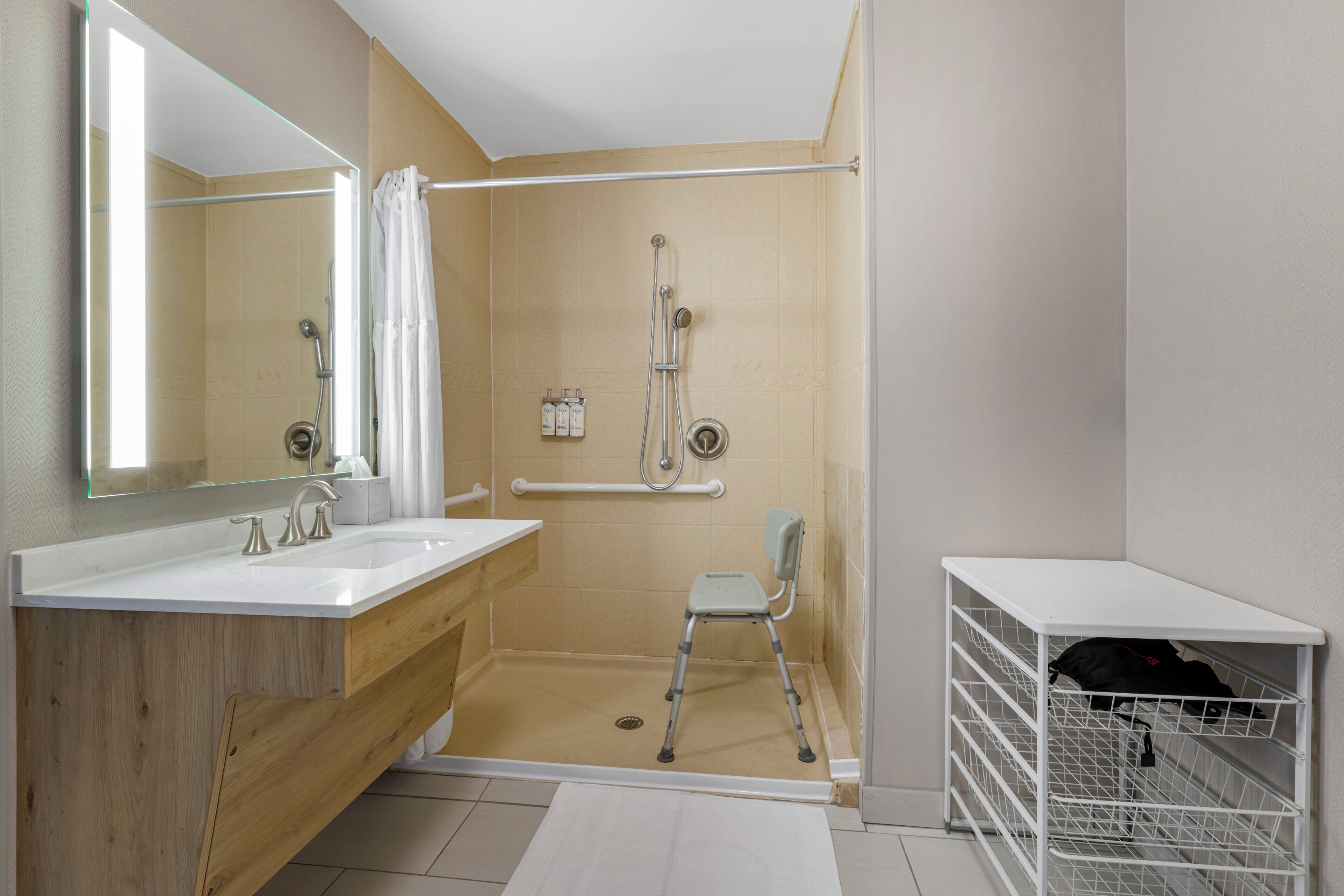 Een badkamer met een douche, wastafel, spiegel en opbergruimte.