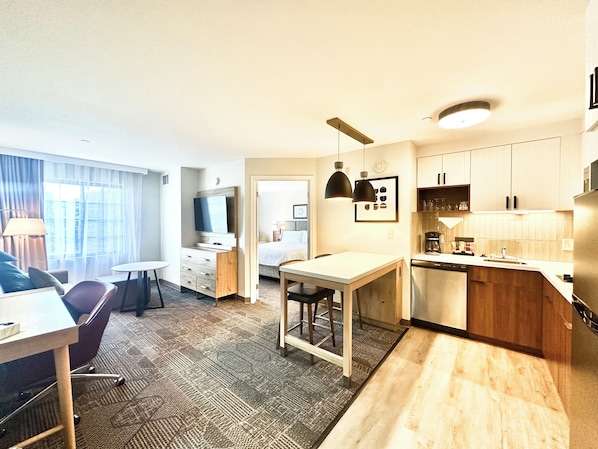 Une chambre d’hôtel moderne dotée d’un coin repas, d’une kitchenette et d’un lit.