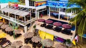 Un bar-restaurant situé en bord de mer, avec une terrasse, un espace piscine et un salon de tatouage.