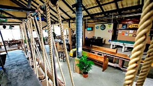 Un restaurant à thème maritime, avec des cordes servant de barrières, des tables en bois et une plante en pot.