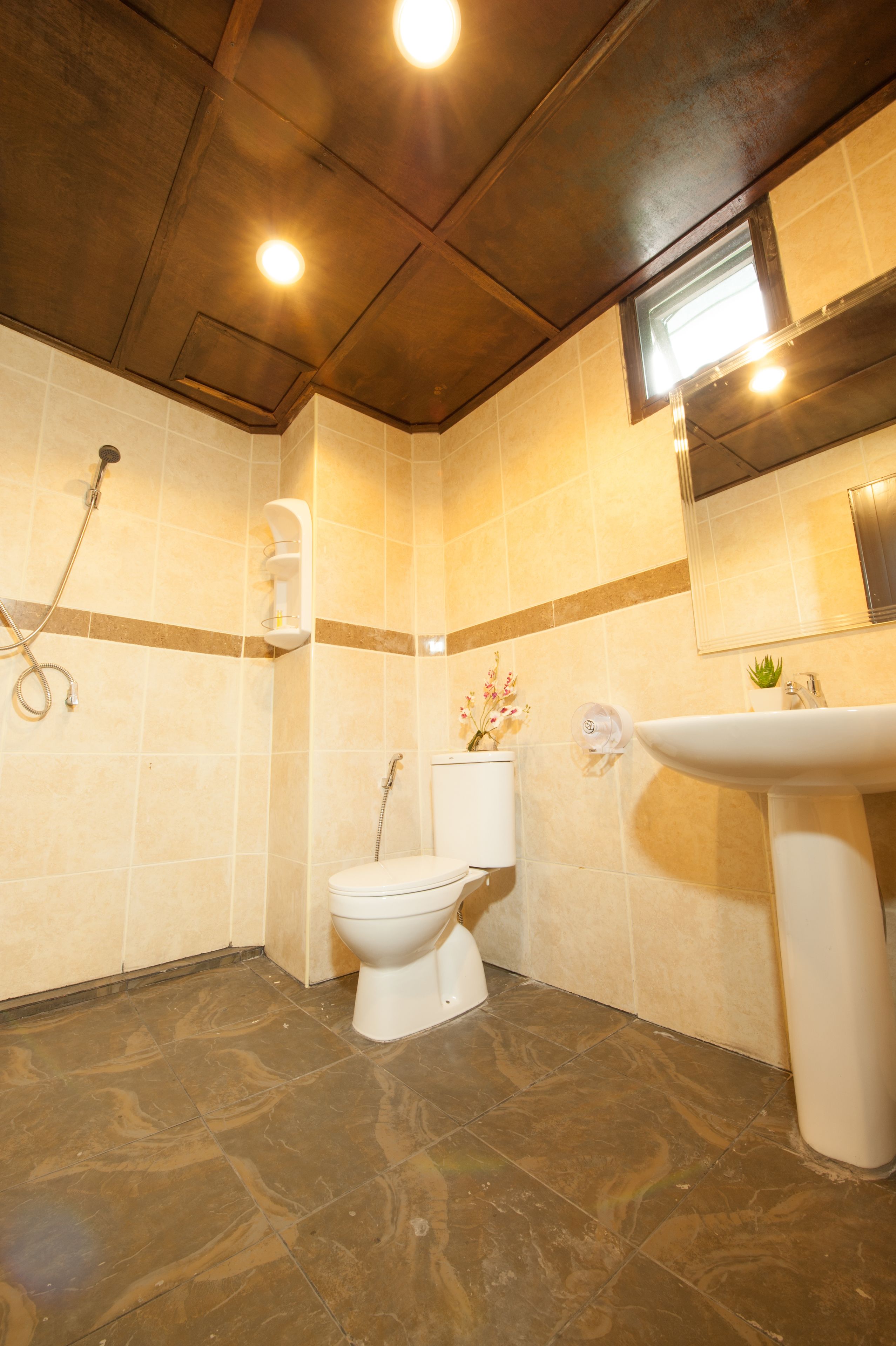 A bathroom with a toilet, shower, sink, and a mirror.