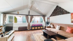 Un salon moderne avec un canapé, une table basse, un téléviseur et une grande fenêtre avec des rideaux.