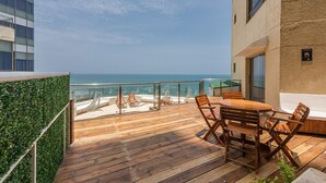 Una terraza de madera con muebles de exterior con vistas a una playa.