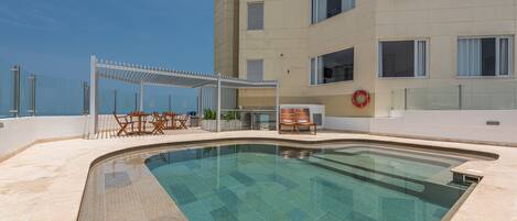 A swimming pool with a sun terrace, outdoor seating, and a lifebuoy on the wall.