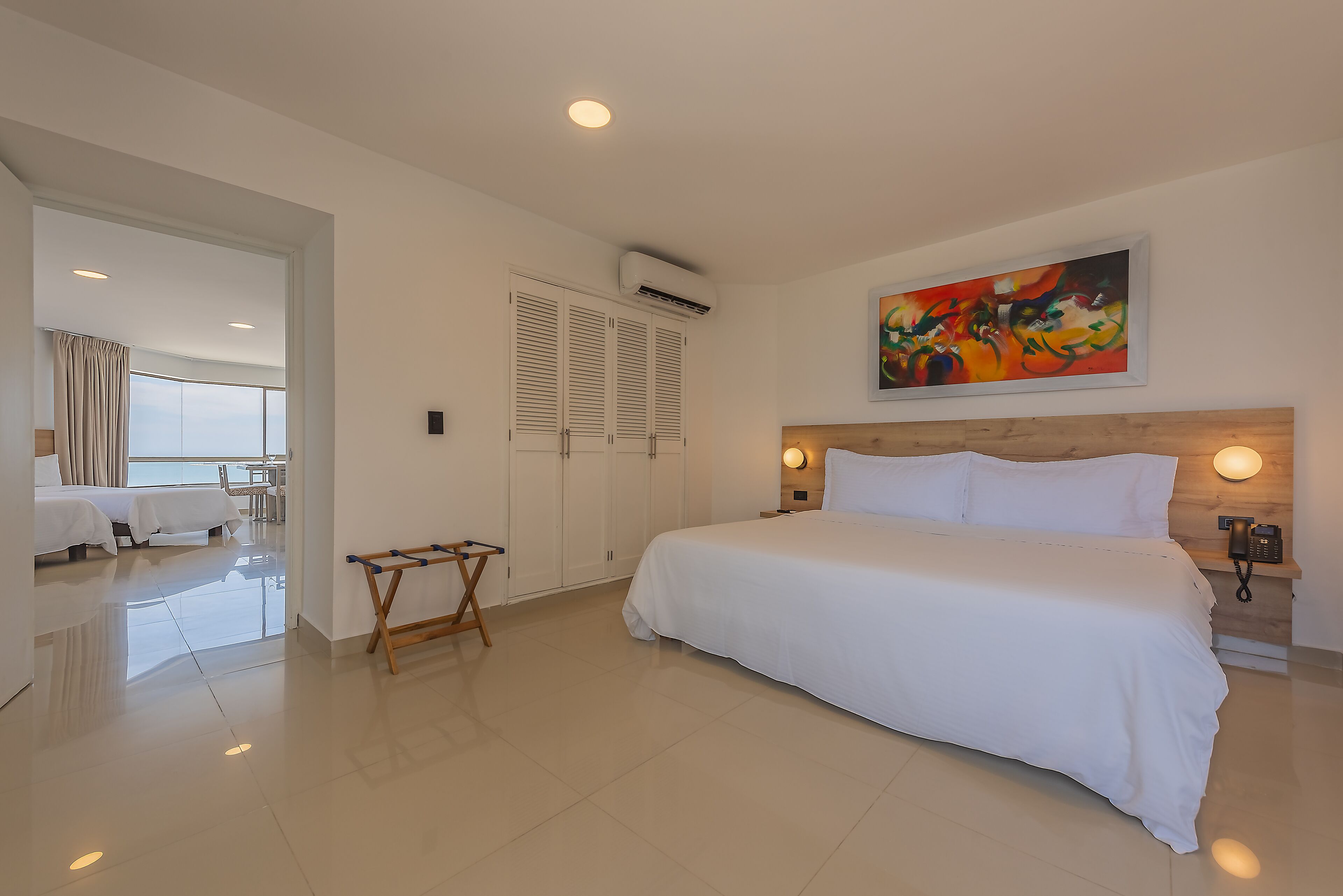 Una camera d'albergo con un letto grande, un quadro appeso alla parete e una testiera in legno.
