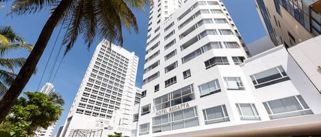 Un hotel moderno con una entrada destacada, varios pisos y una vista despejada del cielo.