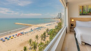 Habitación de hotel con vista a la playa, una cama, una mesita de noche y un cuadro en la pared.