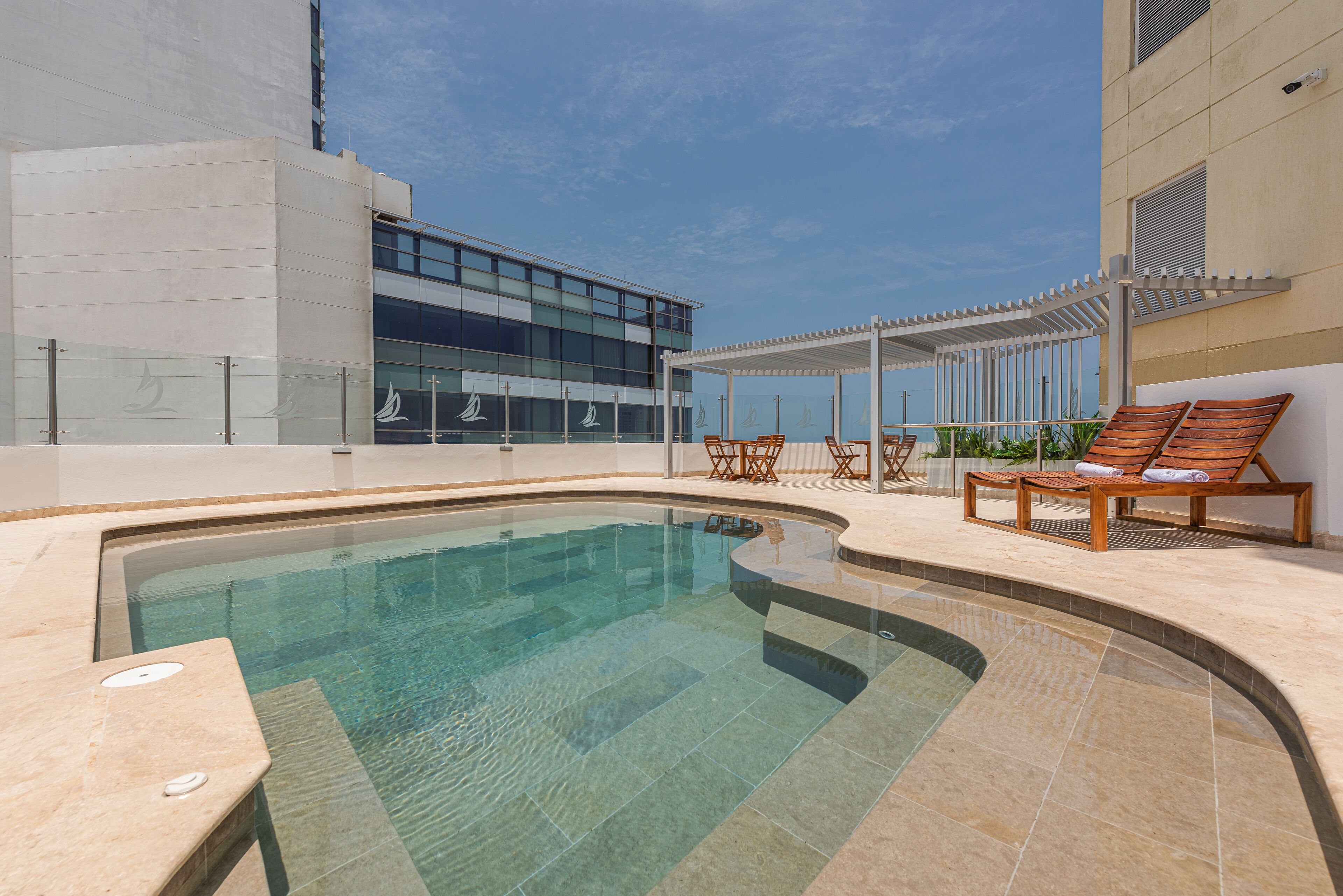 A swimming pool with lounge chairs and a covered seating area.