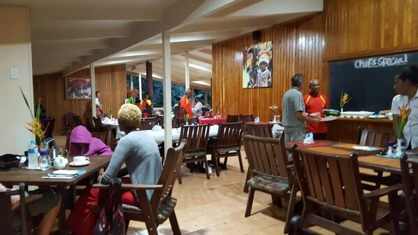 A restaurant with wooden paneling, tables with chairs, and a chalkboard menu.