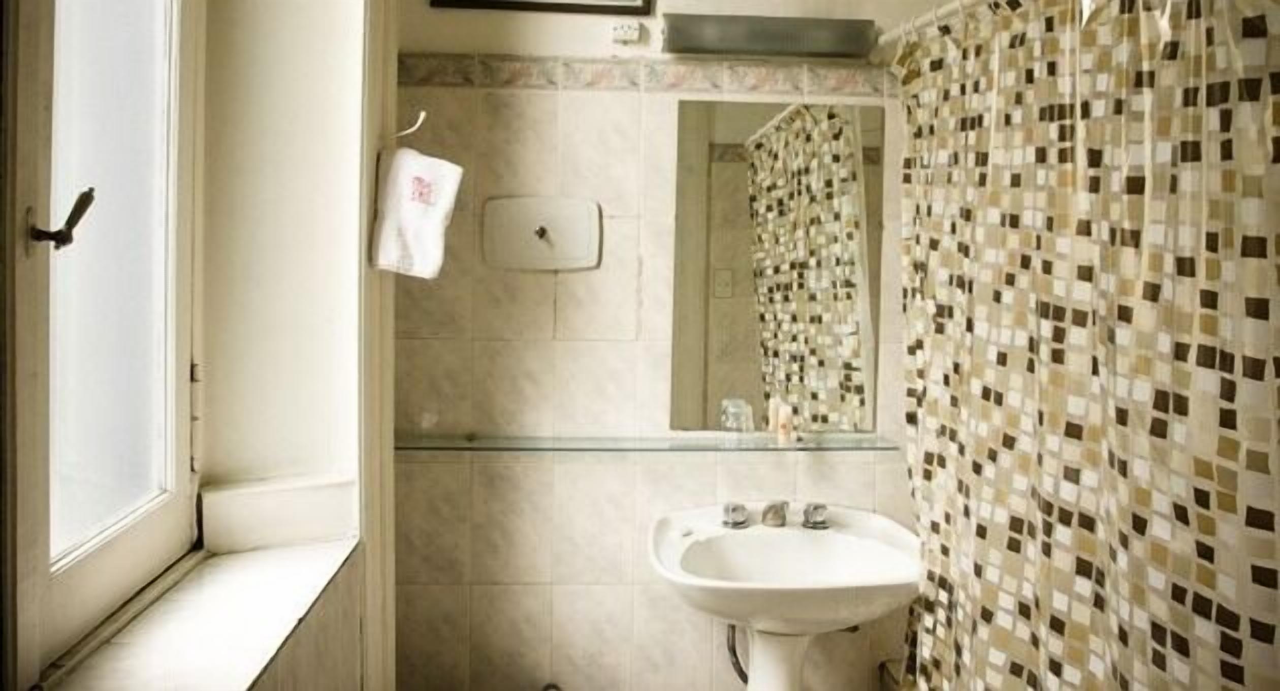 A bathroom with a sink, mirror, and tiled walls.