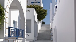 A narrow, white-walled street with a staircase leading to a building entrance. - Lofos Village Hotel (Ios)