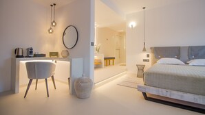 A modern bedroom with a bed, bedside table, and a desk area with a chair. - Lofos Village Hotel (Ios)