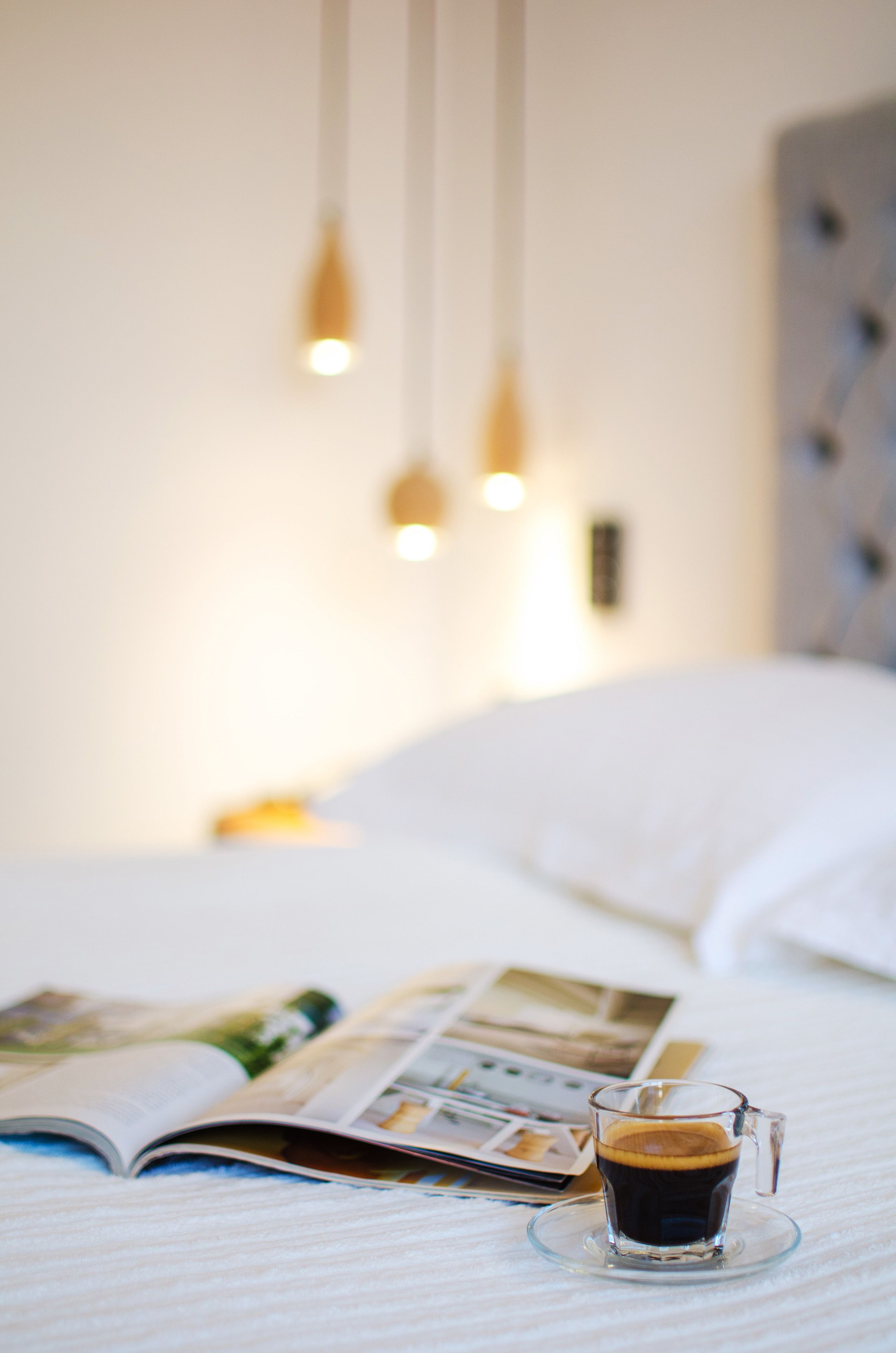 A bed with a magazine and a cup of coffee on it.