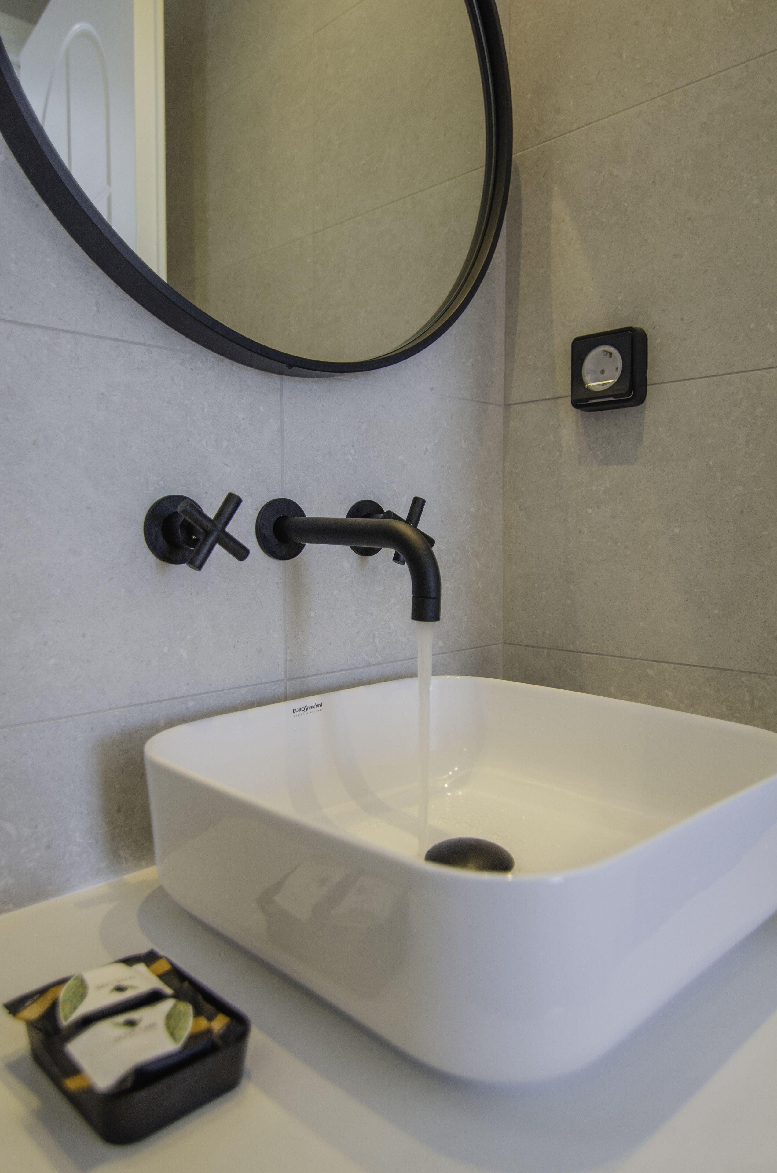 A bathroom with a white sink, black faucet, and a mirror above it.