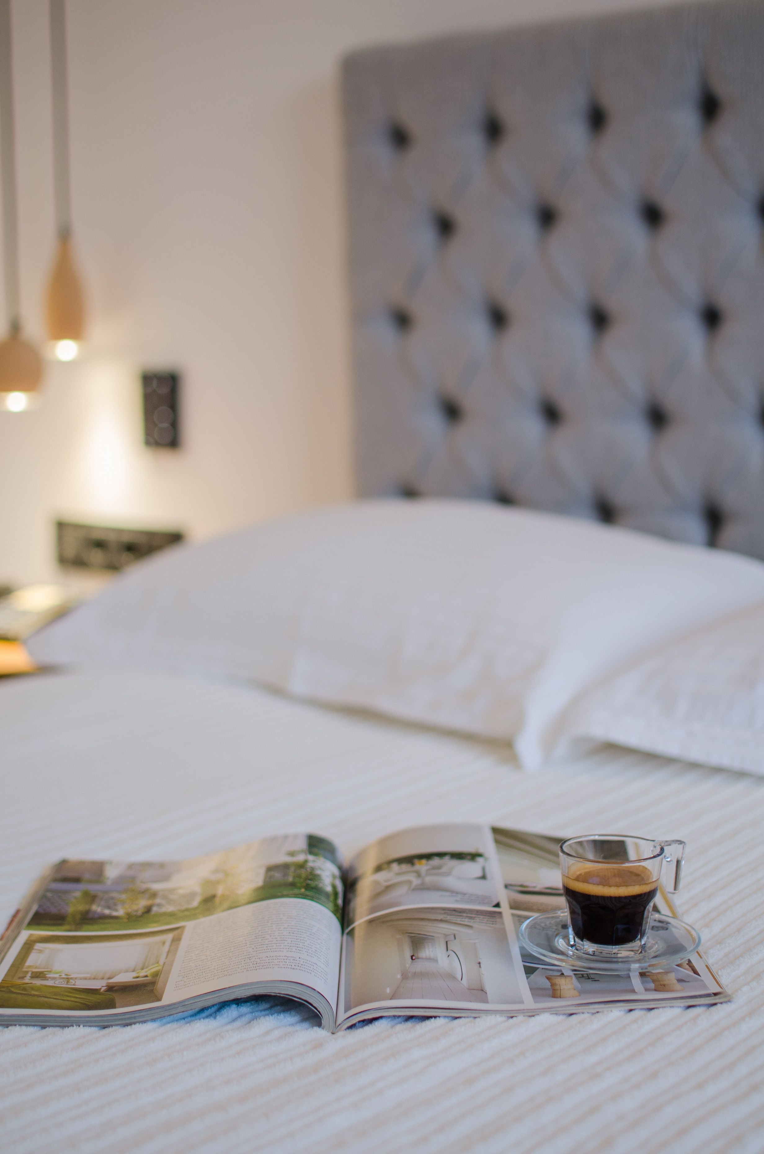 A bed with a magazine and a cup of coffee on it.