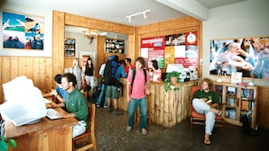 Ein Hostelinterior mit Holzwänden, einem Empfangstresen und einem Bücherregal.
