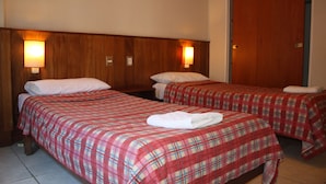 Ein Hotelzimmer mit zwei Betten, einem Holzkopfstück und Wandlampen.