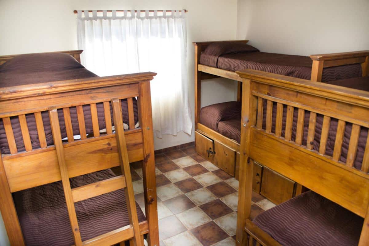 A dormitory room with bunk beds, a tiled floor, and a curtain.