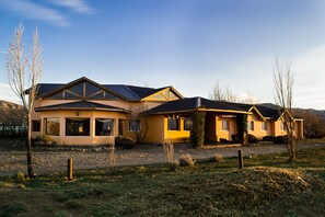 A two-story house with a large front porch and a garage. - Hostel Inn Calafate (El Calafate)