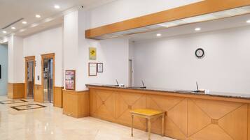 A reception area with a wooden reception desk, a clock on the wall, and a tiled floor.