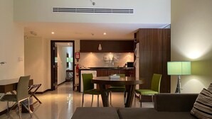 A modern living room with a sofa, a dining table with chairs, and a kitchen area in the background.