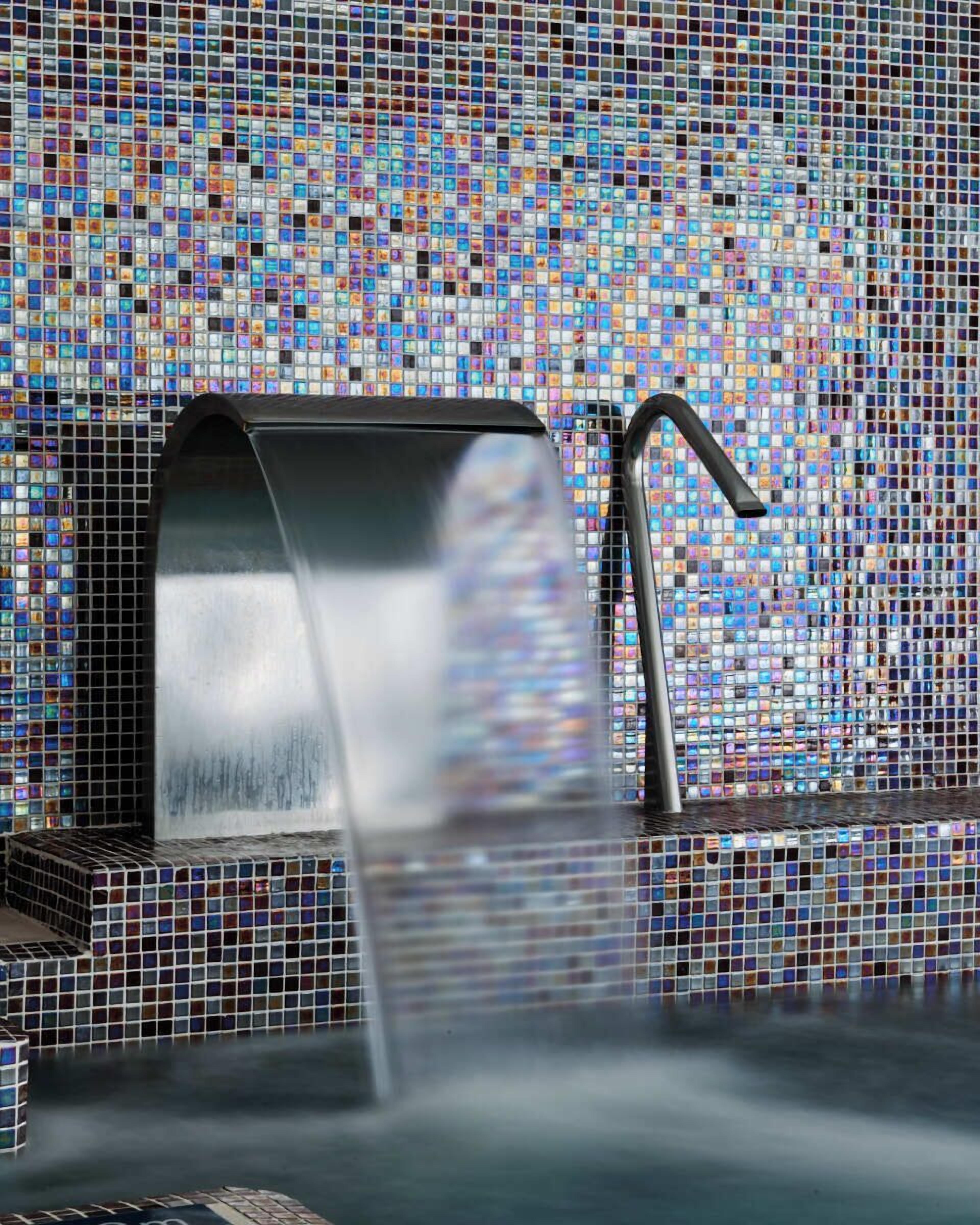 Un baño con pared de mosaicos y un grifo moderno.