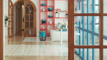 A spacious lobby with a tiled floor, a wooden door frame, a red shelving unit, and a white sofa.