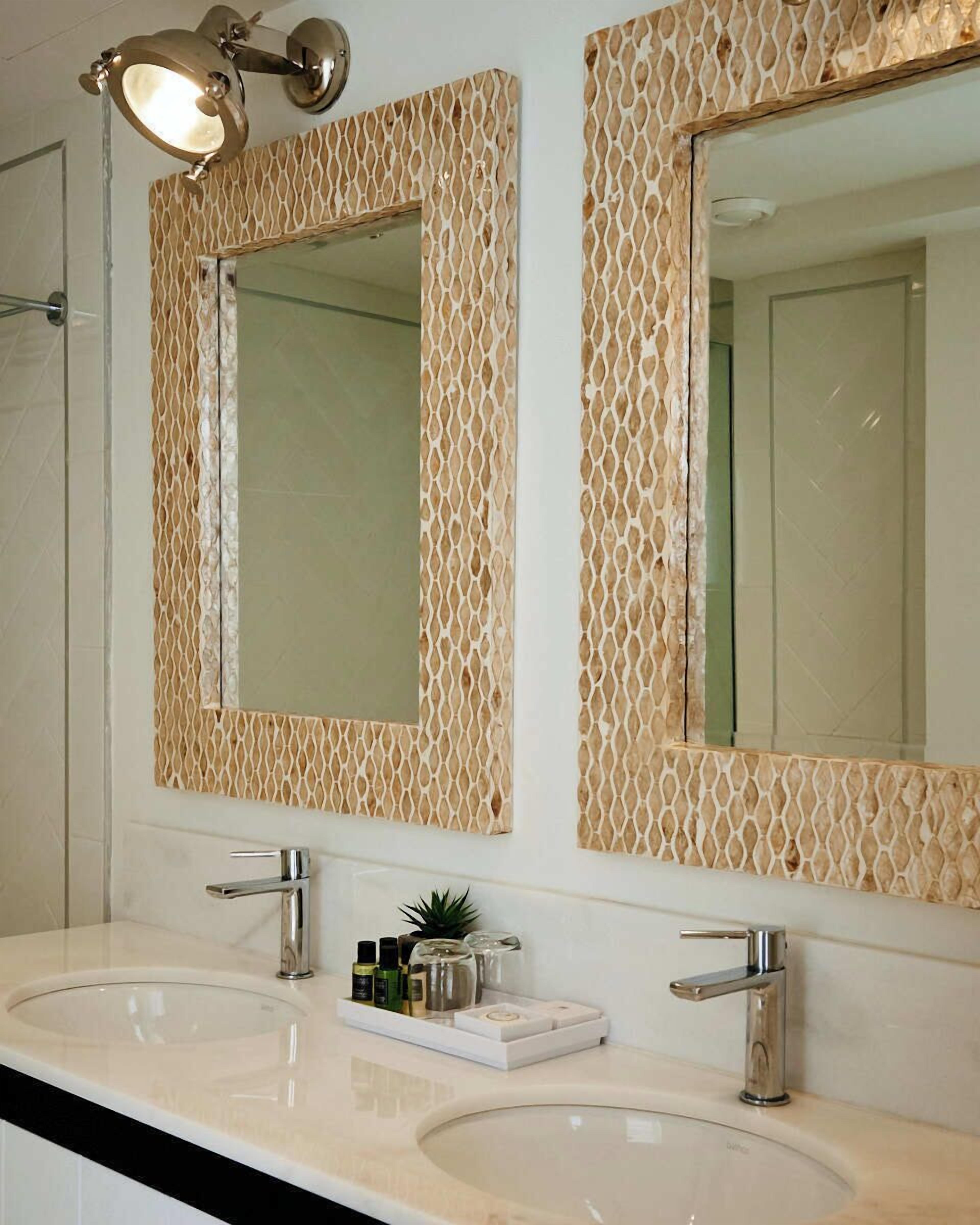 Een badkamer met twee wastafels, een spiegel en een lamp.