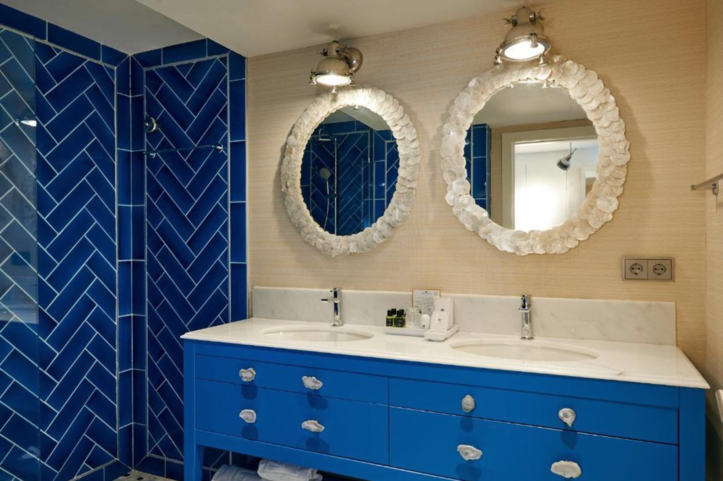 A bathroom with two sinks, blue vanity, and two wall-mounted mirrors.