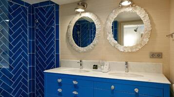 A bathroom with two sinks, blue vanity, and two wall-mounted mirrors.