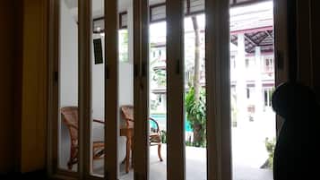 Una habitación con puerta corredera que da a un espacio exterior con mobiliario de mimbre y vista a un edificio con balcones.
