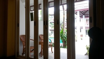 Una habitación con puerta corredera que da a un espacio exterior con mobiliario de mimbre y vista a un edificio con balcones.