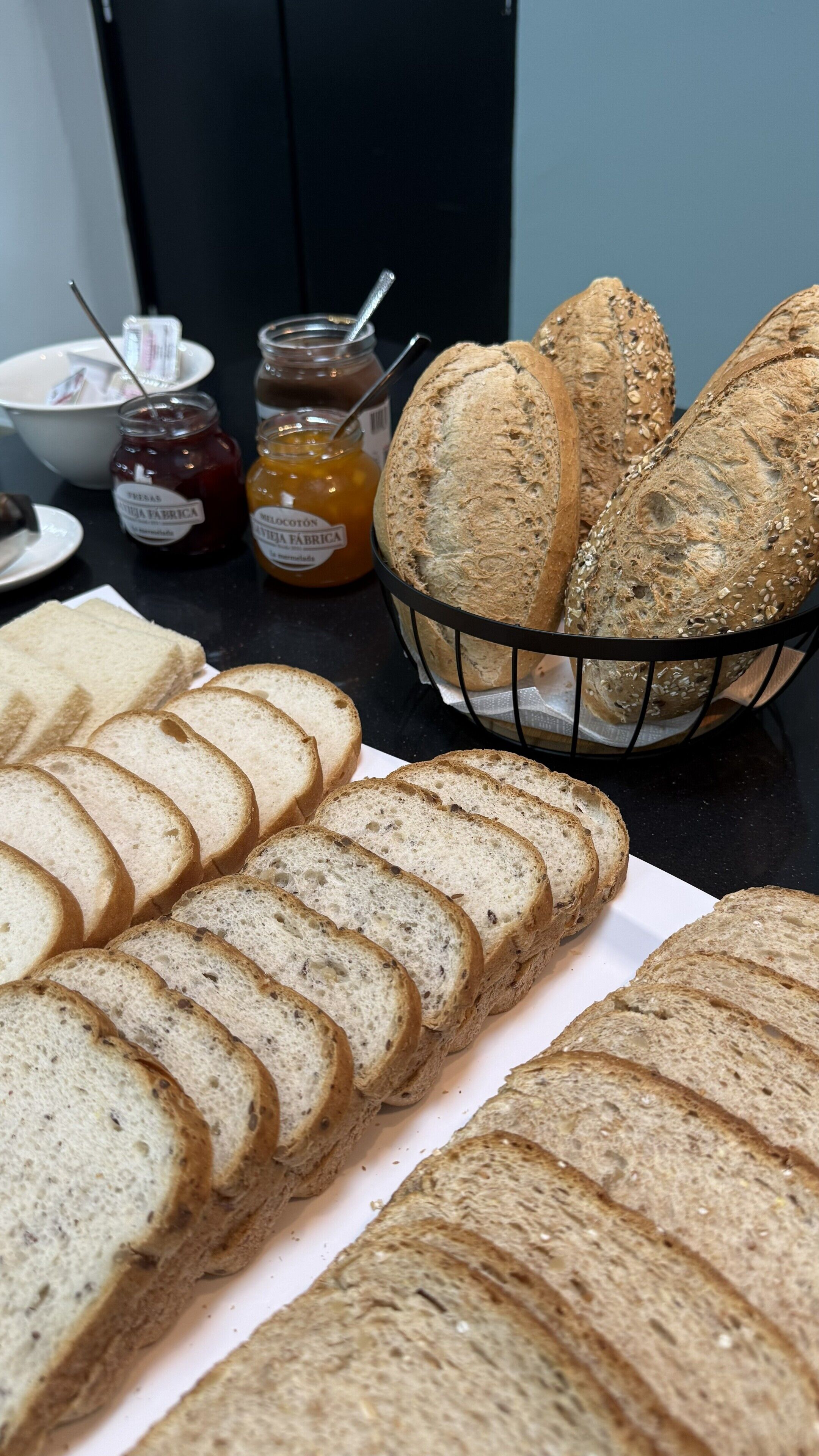 Pan en rebanadas y frascos de mermelada sobre una mesa.
