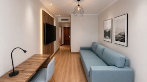 Un salon moderne avec un téléviseur à écran plat, un canapé bleu clair, une table basse en bois et un luminaire suspendu.