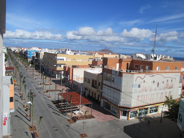 A street view with buildings, palm trees, and a clear sky. - eó Gran Canaria Aeropuerto - Business and Events (Santa Lucia)