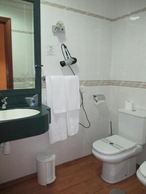 A bathroom with a sink, mirror, towel rack, toilet, and a hairdryer on the wall. - eó Gran Canaria Aeropuerto - Business and Events (Santa Lucia)