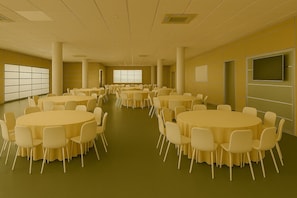 A conference room with multiple round tables and chairs, large windows, and a flat-screen TV on the wall.