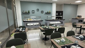 Un espace repas moderne avec des tables et des chaises, un buffet et des étagères décoratives murales.