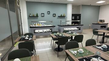 Ein stilvoller Essbereich mit Tischen, Stühlen, einem Buffet und dekorativen Wandregalen.