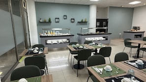 A modern dining area with tables and chairs, a buffet counter, and decorative wall shelves.