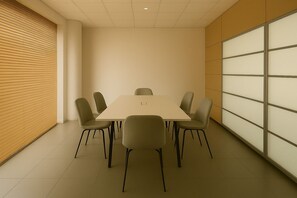Een vergaderruimte met een rechthoekige tafel en zes stoelen, een wand van houten latten en een glazen scheidingswand.