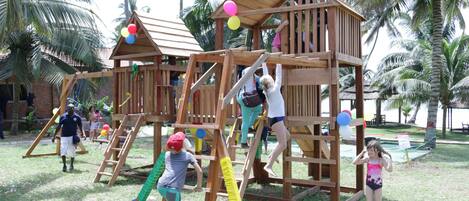 Una estructura de juegos de madera con elementos para escalar y un tobogán.